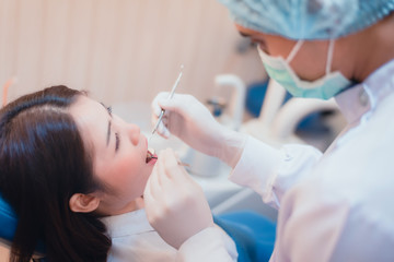 Attractive young woman in stomatology clinic with male dentist. Healthy teeth concept.