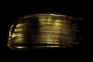 Creative brushstrokes of gold paint isolated on a black background. Gold paint texture.Acrylic gold paint. Smears of cosmetics, blush, highlighter, eye shadow, lipstick.