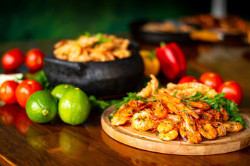 garlic and oil shrimp served on wooden board with lemon clay pot