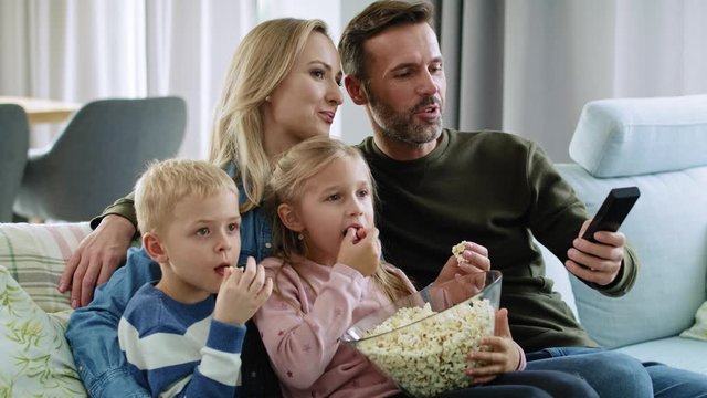 Family with two children watching tv in living room