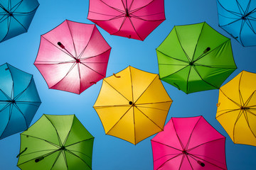 Multiple coloured umbrellas with a blue sky background