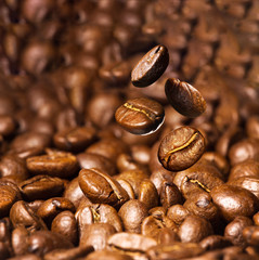 Roasted coffee beans. Seeds of freshly roasted coffee with smoke. Coffee beans closeup with emphasis on the grain with smoke.