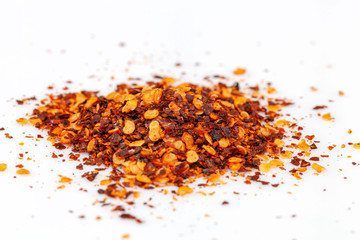 pile crushed red cayenne pepper, dried chili flakes and seeds isolated on white background