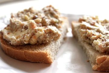 Mincemeat of herring on a slice of brown bread on white background close up view