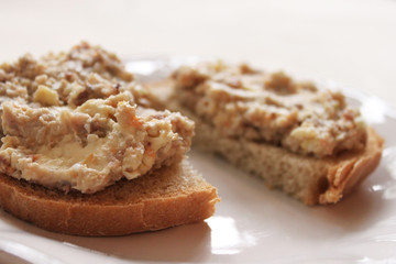 Fototapeta na wymiar Mincemeat of herring on a slice of brown bread on white background close up view