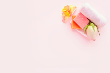 Soap, rose, rose petals and towel on pink background. Concept of natural spa cosmetics. Flat lay, top view, copy space .