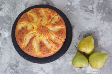 Homemade pear pie on a grey table with pears in the background.