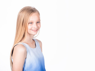 Fototapeta premium Charming happy young girl introducing herself to new classmates. Portrait of a pleased carefree adorable daughter with blond hair in white-blue blouse, standing casually and smiling friendly.