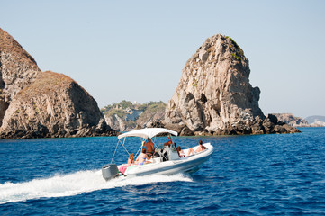 Motor boat at sea. Faraglioni and rocks of the island of Ponza (Italy). Concept of a family on vacation.