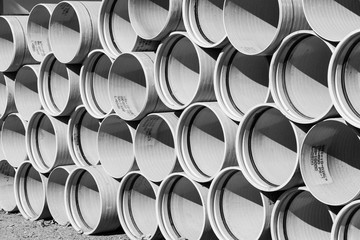 Abstract black and white industrial background, a stack of large pipes for a sewer street.