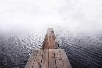 Obraz premium front view of wooden pier going into the water and fog,