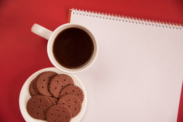 A white Cup of tea, notebook and Chocolate cookies stands on a white background. copy space, flat lay.