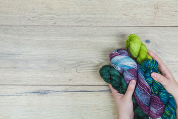 Human hands holding a group of skeins on a wooden table