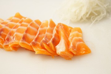 salmon sashimi on cutting board with  radish Shredded