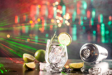 Glass with alcoholic drink with lime, ice and rosemary