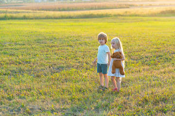 Happy children girl and boy running on meadow in summer in nature. Country life. Happy children farmers having fun on spring field.