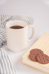 A white Cup of tea, book and Chocolate cookies stands on a white background. open book and cup of coffee.