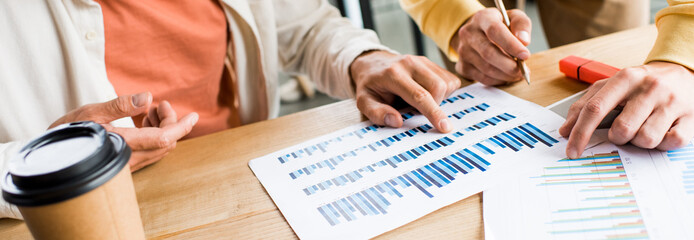 cropped view of businesspeople analyzing graphs and charts in office