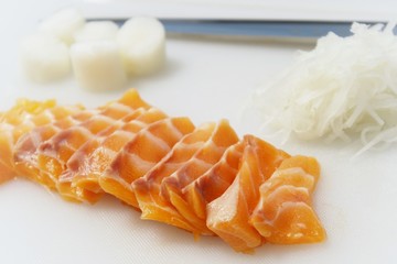 salmon sashimi on cutting board with  radish Shredded