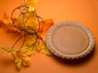 Pumkin pie and fall colored leaves signifing the beginning of autumn and the holiday season .