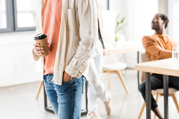 cropped view of young businessman in casual clothing holding coffee to go