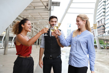 Successful multiethnic business people are clinking glasses of champagne with smiling while celebrating outdoor