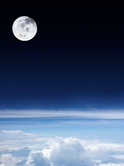 Horizontal clouds with bright blue sky below and dark space above with beautiful full moon.Image of moon furnished by NASA.