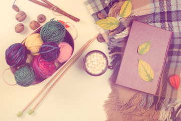 Autumn knitting background. Basket with balls of wool, autumn leaves, and knitting needles. Autumn...
