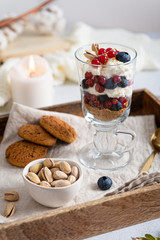 Blueberry dessert, cheesecake, trifle, mousse in a glass on a wooden tray with pistachios and oatmeal cookies. Side view. Cozy autumn composition. Confectionery