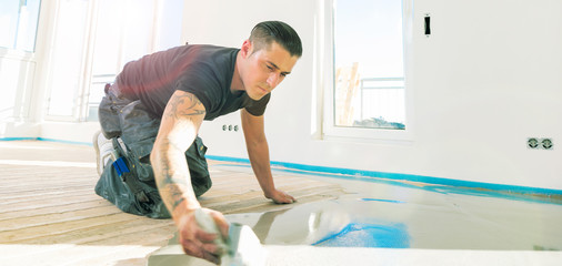 männliche Arbeitskraft, die mit selbstnivellierendem Zementmörtel während der Bodensanierung...