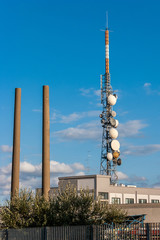 Obraz premium Urban Scene with telecommunication tower and industrial chimneys