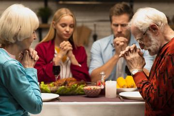 Family praying at the dinner table front view