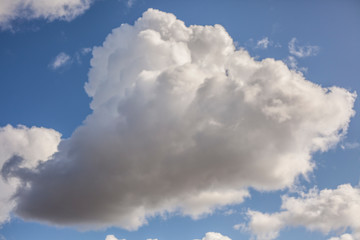 One white cloud. A cumulus cloud floats in the sky. Beautiful aerial mountain on the blue sky. Background calm heights.