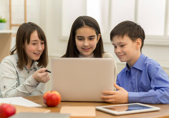 Obraz premium School girls and boy playing on laptop in school