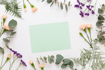 Flowers composition. Paper blank, carnation flowers, eucalyptus branches on pastel  background....