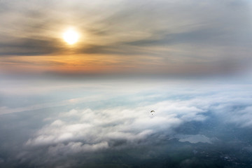 Fototapeta premium Paragliding in the sun above the clouds from above