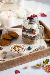 Blueberry dessert, cheesecake, trifle, mousse in a glass on a wooden tray with pistachios and oatmeal cookies. Side view. Cozy autumn composition. Confectionery
