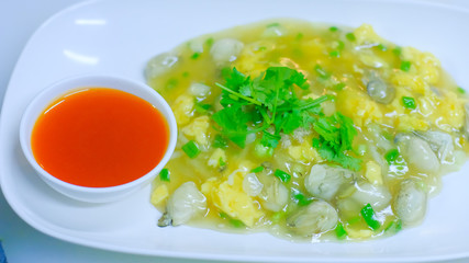 Selective focus of Chinese oyster omelette with chili sauce in white plate.