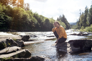 girl hiker on the bank of a mountain river