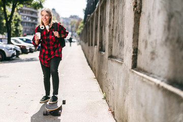 Fototapeta na wymiar Young woman holding coffee while skating 