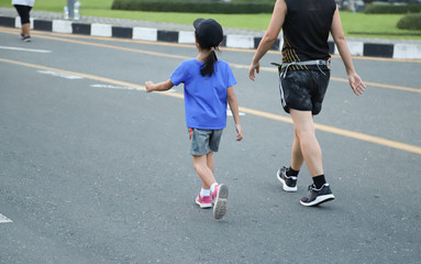 Fototapeta premium Closeup of Asian man and girl walking together in jogging track on the street. Lovely and healthy family activity. 