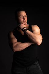 Fototapeta na wymiar Strong and handsome young man with muscles and biceps. Studio shooting on black background.