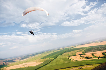 A paraglider flies in the sky in a cocoon suit on a paraglider over the Caucasian countryside with...