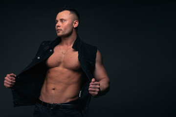 Strong and handsome young man with muscles and biceps. Studio shooting on black background.