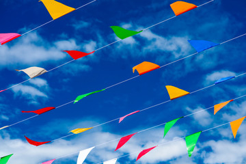colorful triangular flag line moving by wind on blue sky white cloud