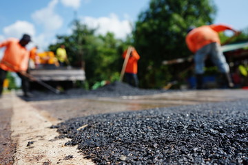 Repairing a damaged road By adjusting the level with asphalt mixed with small stones (picture blurred)