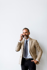Senior businessman using mobile phone against wall in office