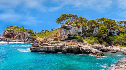 Obraz premium Panorama of beautiful beach and bay with cliffs, trees and turquoise sea water, Cala sAlmunia, Santanyi, Mallorca island, Spain