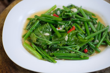 Stir Fried Chayote leaf with chili and garlic on white plate , Thai food.