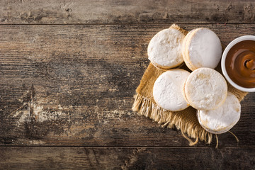 Traditional Argentinian alfajores with dulce de leche and sugar on wooden table. Top view. Copy...